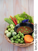 Chili paste paste in a bowl with eggplant, carrots, chili, cucumbers in a basket on wood table. Стоковое фото, агентство Ingram Publishing / Фотобанк Лори