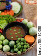 Chili paste paste in a bowl with eggplant, carrots, chili, cucumbers in a basket on wood table. Стоковое фото, агентство Ingram Publishing / Фотобанк Лори