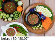 Chili paste paste in a bowl with eggplant, carrots, chili, cucumbers in a basket on wood table. Стоковое фото, агентство Ingram Publishing / Фотобанк Лори