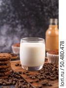 Milk in a glass, complete with coffee beans, cupcakes, bananas and cookies on a wooden plate. Стоковое фото, агентство Ingram Publishing / Фотобанк Лори