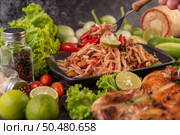Thai papaya salad in a black plate consisting of papaya, chili, tomatoes, peanuts, and lime. Стоковое фото, агентство Ingram Publishing / Фотобанк Лори
