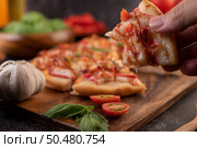 Pizza placed on a wooden plate complete with pepper seeds. Tomatoes and garlic. Стоковое фото, агентство Ingram Publishing / Фотобанк Лори
