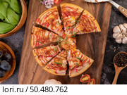 Pizza placed on a wooden plate complete with pepper seeds. Tomatoes and garlic. Top view. Стоковое фото, агентство Ingram Publishing / Фотобанк Лори