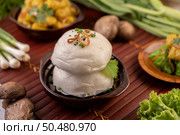 Steamed buns in a wooden dish on a wooden grill. Selective focus. Стоковое фото, агентство Ingram Publishing / Фотобанк Лори
