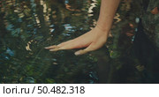 A hand barely touches the surface of a clear rippling pool of cenote in the jungle of Yucatan Mexico. Стоковое видео, видеограф Igor Tichonow / Фотобанк Лори