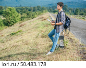 Male traveler with a backpack Holding a map and standing near to a kilometer. Стоковое фото, агентство Ingram Publishing / Фотобанк Лори