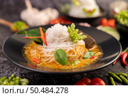Chicken curry in a black cup with rice noodles, garlic, tomatoes, chilies, and kaffir lime leaves. Стоковое фото, агентство Ingram Publishing / Фотобанк Лори