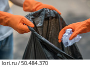 Men and women helped to collect garbage in a black bag. Стоковое фото, агентство Ingram Publishing / Фотобанк Лори
