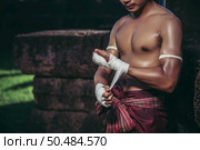 The boxer sat on the stone, tied the tape around his hand, preparing to fight. Стоковое фото, агентство Ingram Publishing / Фотобанк Лори