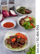 Fried pork topped with sesame, complete with tomatoes, cucumbers, cabbage, and lettuce placed in a white dish. Стоковое фото, агентство Ingram Publishing / Фотобанк Лори