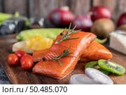 Raw salmon fillets, pepper, kiwi, pineapple and rosemary, wood chopping boards and black cement floors. Стоковое фото, агентство Ingram Publishing / Фотобанк Лори