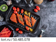 Raw salmon fillets, pepper, kiwi, pineapples, and rosemary onto a plate and black cement floor. Стоковое фото, агентство Ingram Publishing / Фотобанк Лори