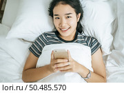 Young women wearing striped shirts playing smart phones. Selective focus. Стоковое фото, агентство Ingram Publishing / Фотобанк Лори
