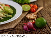 Thai style spicy food, Som Tum food concept, props decoration Garlic, lemon, peanuts, tomatoes, and shallots on wood table. Стоковое фото, агентство Ingram Publishing / Фотобанк Лори