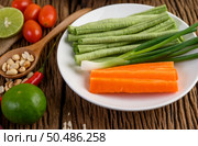 Thai style spicy food, Som Tum food concept, props decoration Garlic, lemon, tomatoes, chili, long-hatched beans, spring onions, shallots,  and carrots and peanuts on wood spoon on wood table. Стоковое фото, агентство Ingram Publishing / Фотобанк Лори