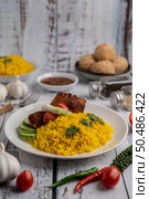 Chicken Biryani in a plate with spices on a white wooden floor. Стоковое фото, агентство Ingram Publishing / Фотобанк Лори