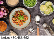 Spicy minced pork salad with chili flakes, lime, chopped green onions, chilli and roasted rice, sliced ??shallots on a cement floor. Стоковое фото, агентство Ingram Publishing / Фотобанк Лори
