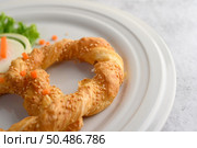 Freshly baked soft pretzel with generous sprinkling of coarse salt and sesame on white dish, decorate with lettuce and carrot beautifully, copy space. Стоковое фото, агентство Ingram Publishing / Фотобанк Лори