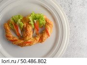 Freshly baked soft pretzel with generous sprinkling of coarse salt and sesame on white dish, decorate with lettuce and carrot beautifully, copy space. Стоковое фото, агентство Ingram Publishing / Фотобанк Лори
