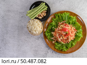 Thai papaya salad on salad in a wooden plate with Sticky rice, Yardlong beans, and garlic. Top view. Стоковое фото, агентство Ingram Publishing / Фотобанк Лори