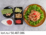 Thai papaya salad on salad in a wooden plate with Yardlong beans and garlic, Top view. Стоковое фото, агентство Ingram Publishing / Фотобанк Лори
