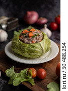 Pork cabbage soup with carrots, chopped green onions, cucumber in a wooden plate on a wooden plate. Стоковое фото, агентство Ingram Publishing / Фотобанк Лори