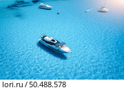 Aerial view of beautiful luxury yacht and sailboats in blue sea at sunset in summer. Sardinia island, Italy. Top view of speed boat, sea coast, transparent water. Travel. Tropical landscape. Yachting . Стоковое фото, агентство Ingram Publishing / Фотобанк Лори