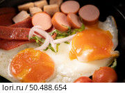 Breakfast with fried eggs, sausage, and ham in a pan with tomatoes. Chili and basil. Стоковое фото, агентство Ingram Publishing / Фотобанк Лори