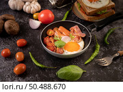 Breakfast with fried eggs, sausage, and ham in a pan with tomatoes. Chili and basil. Стоковое фото, агентство Ingram Publishing / Фотобанк Лори