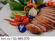 Sliced ??fried pork with lemon, onion, red onion, tomato, long bean, butterfly pea flower, and mint. Стоковое фото, агентство Ingram Publishing / Фотобанк Лори