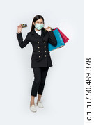 A woman in black and wearing a mask walks shopping, carries credit cards, and lots of bags. Стоковое фото, агентство Ingram Publishing / Фотобанк Лори