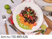 Sweet pork in a white plate with chopped scallions, chili, lime, gourd, tomato and garlic. Стоковое фото, агентство Ingram Publishing / Фотобанк Лори