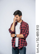 A man with a migraine headache holding her hand in her nose. Стоковое фото, агентство Ingram Publishing / Фотобанк Лори