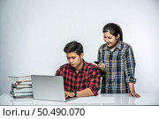 Women teach men how to work with laptops at work. Стоковое фото, агентство Ingram Publishing / Фотобанк Лори