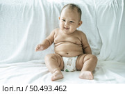 A baby learns to sit on a white bed. Стоковое фото, агентство Ingram Publishing / Фотобанк Лори