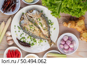 Two cooked mackerel, placed in a white dish, sprinkled with spring onions. Стоковое фото, агентство Ingram Publishing / Фотобанк Лори