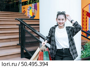 Portrait beautiful woman place eyeglasses on head holding shopping bags in hand sit on the iron railing,  she smile and looking to camera,  Lifestyle and shopping concept. Стоковое фото, агентство Ingram Publishing / Фотобанк Лори