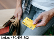 Select focus credit card in hand of Young handsome man in mask, He holding paper bag and show credit card on stair of shopping mall, New normal lifestyle and shopping concept, copy space. Стоковое фото, агентство Ingram Publishing / Фотобанк Лори