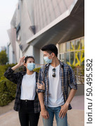 Asian Young Couple in protection mask standing outdoor of large building, They are discussion with happiness, New normal lifestyle amid coronavirus outbreak. Стоковое фото, агентство Ingram Publishing / Фотобанк Лори