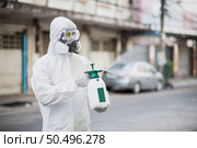 Disinfection specialist man in personal protective equipment (ppe) suit, gloves, mask and face shield, cleaning Quarantine area with a bottle of pressurized spray disinfectant to remove coronavirus. Стоковое фото, агентство Ingram Publishing / Фотобанк Лори