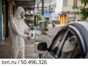 Disinfection specialist man in personal protective equipment (ppe) suit, gloves, mask and face shield, cleaning Quarantine area with a bottle of pressurized spray disinfectant to remove covid-19. Стоковое фото, агентство Ingram Publishing / Фотобанк Лори