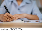 Selective focus hand of asian young woman in eyeglasses use pen working with papers at home office, during quarantine covid-19 self isolation at home, work from home concept. Стоковое фото, агентство Ingram Publishing / Фотобанк Лори
