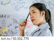 Young asian woman standing and thoughtful how to present planing of project on board in meeting room, copy space. Стоковое фото, агентство Ingram Publishing / Фотобанк Лори