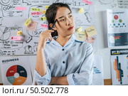 Young asian woman standing and thoughtful how to present planing of project on board in meeting room, copy space. Стоковое фото, агентство Ingram Publishing / Фотобанк Лори