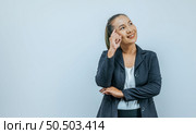 Portrait of smiling Asian woman wearing casual clothes pointing to head with one finger and looking away at empty space aside, isolated over background in studio. Стоковое фото, агентство Ingram Publishing / Фотобанк Лори