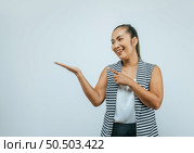 Portrait of Asian woman over isolated background in studio with blank space. Smiling aside while presenting with hand and pointing with finger. Стоковое фото, агентство Ingram Publishing / Фотобанк Лори