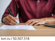 Male employee signing paperwork to approve work at desk. Стоковое фото, агентство Ingram Publishing / Фотобанк Лори