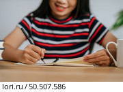 a young woman working in a book on the table. Стоковое фото, агентство Ingram Publishing / Фотобанк Лори