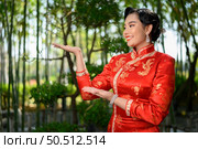 Portrait beautiful Asian woman in a Chinese cheongsam spreads her palm as blank space to insert picture for advertisement, copy space. Стоковое фото, агентство Ingram Publishing / Фотобанк Лори