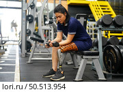 Young female with one prosthetic leg warms up by lifting light weights. Concept of living a woman’s life with a prosthetic limb. Стоковое фото, агентство Ingram Publishing / Фотобанк Лори